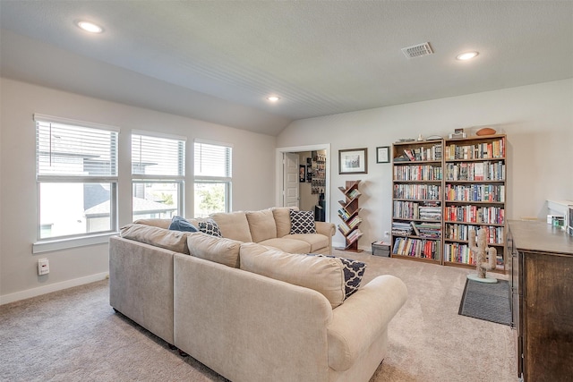 living room featuring a textured ceiling, vaulted ceiling, and light colored carpet