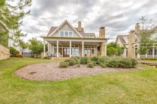 back of property featuring ceiling fan, a lawn, and a porch