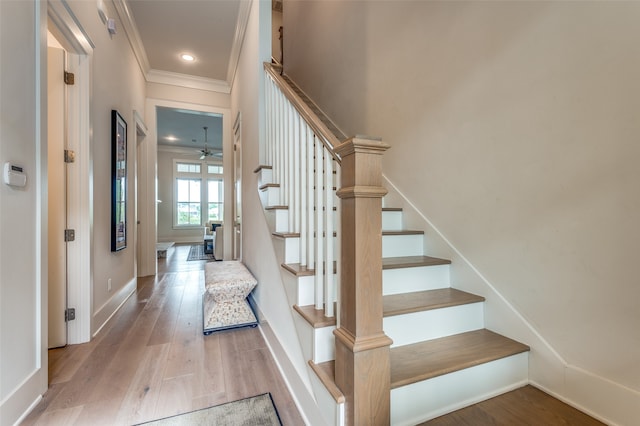 stairway with ornamental molding, hardwood / wood-style floors, and ceiling fan