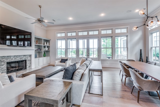 living room featuring french doors, light hardwood / wood-style flooring, a high end fireplace, crown molding, and ceiling fan