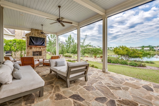 view of patio / terrace with an outdoor living space with a fireplace, a water view, and ceiling fan