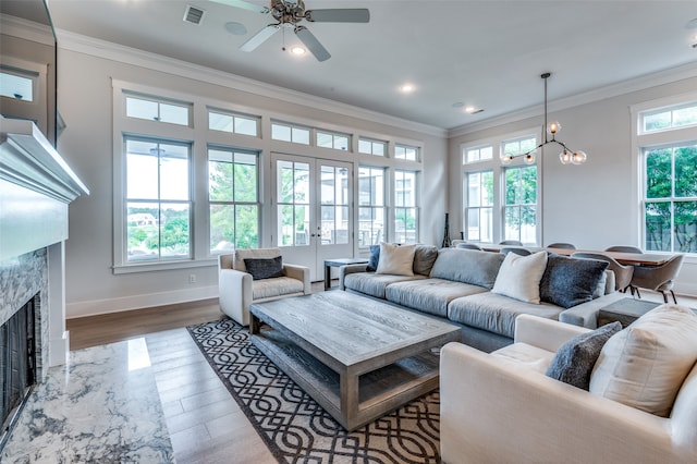 living room featuring a healthy amount of sunlight, wood-type flooring, and ceiling fan with notable chandelier