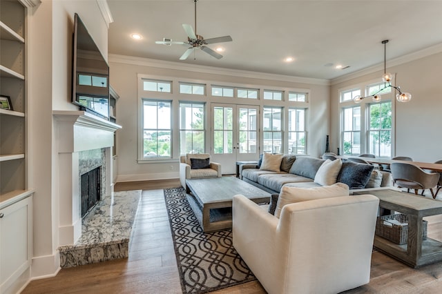 living room featuring ornamental molding, a fireplace, wood-type flooring, and ceiling fan with notable chandelier