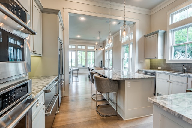 kitchen with a healthy amount of sunlight, sink, pendant lighting, and a breakfast bar area