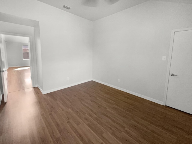 unfurnished room featuring baseboards, a ceiling fan, wood finished floors, and visible vents