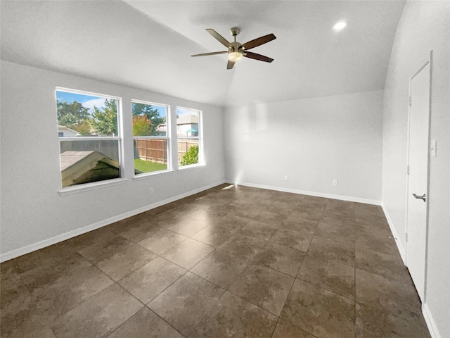 unfurnished room featuring baseboards, a ceiling fan, lofted ceiling, and dark tile patterned flooring
