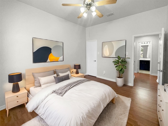 bedroom featuring connected bathroom, dark wood-type flooring, and ceiling fan