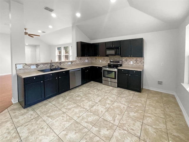 kitchen with appliances with stainless steel finishes, a sink, lofted ceiling, backsplash, and visible vents
