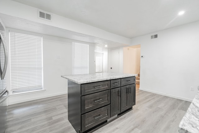 kitchen featuring light stone counters, light hardwood / wood-style flooring, and a kitchen island