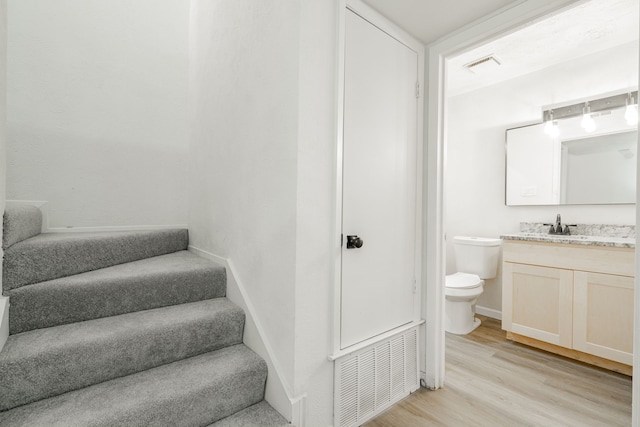 stairs with wood-type flooring and sink