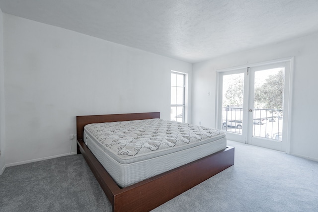 carpeted bedroom with a textured ceiling and access to outside