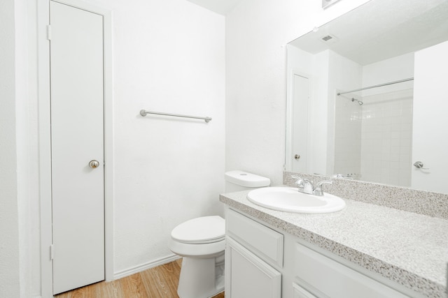 bathroom with vanity, a shower, hardwood / wood-style flooring, and toilet