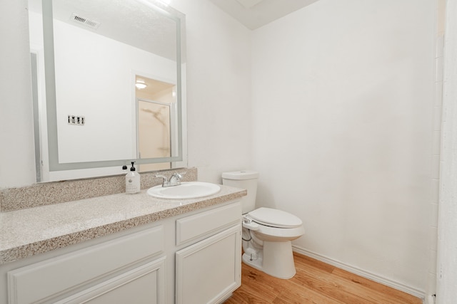 bathroom featuring toilet, walk in shower, hardwood / wood-style flooring, and vanity