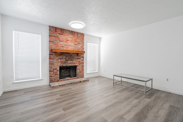 unfurnished living room with light hardwood / wood-style flooring, a textured ceiling, and a fireplace