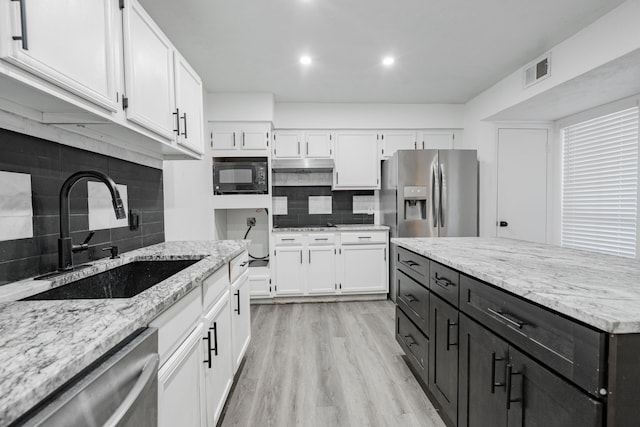 kitchen with appliances with stainless steel finishes, white cabinetry, sink, and light wood-type flooring