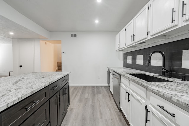 kitchen featuring white cabinets, tasteful backsplash, dishwasher, light hardwood / wood-style floors, and sink