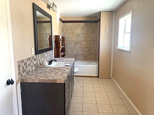 full bathroom with tile patterned floors, toilet, backsplash, tiled shower / bath, and vanity