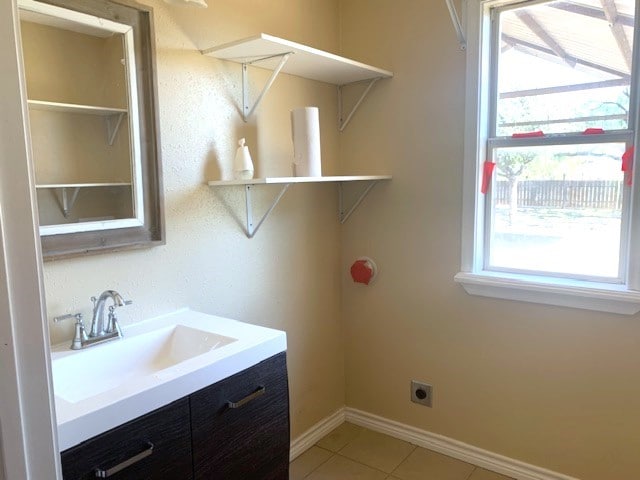 clothes washing area with hookup for an electric dryer, sink, and light tile patterned floors