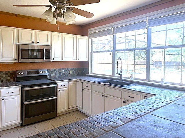 kitchen featuring tile countertops, appliances with stainless steel finishes, and white cabinets