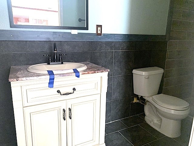 bathroom featuring vanity, toilet, tile patterned floors, and tile walls