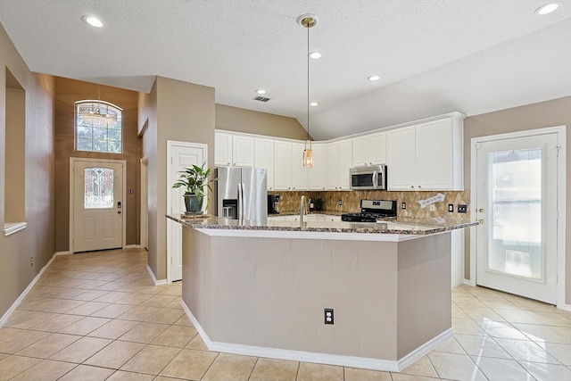 kitchen featuring a kitchen island with sink, a textured ceiling, appliances with stainless steel finishes, light stone counters, and white cabinetry