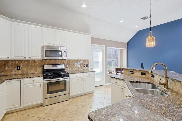 kitchen with appliances with stainless steel finishes, sink, decorative light fixtures, white cabinets, and lofted ceiling