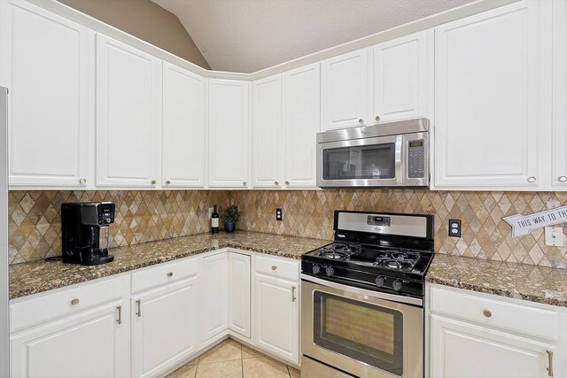 kitchen with white cabinets, dark stone counters, lofted ceiling, and appliances with stainless steel finishes