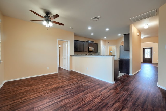 kitchen with kitchen peninsula, ceiling fan, appliances with stainless steel finishes, dark hardwood / wood-style flooring, and light stone countertops