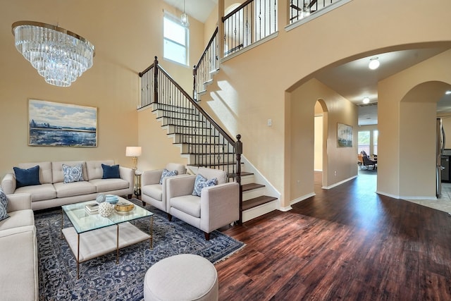 living room featuring dark wood-type flooring, a towering ceiling, and a chandelier