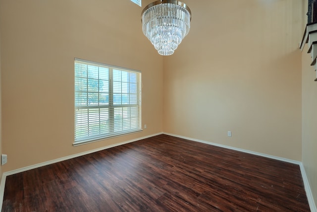 unfurnished room with a high ceiling, dark hardwood / wood-style floors, and an inviting chandelier