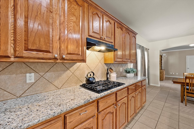 kitchen with decorative backsplash, light tile patterned floors, black gas cooktop, and light stone countertops