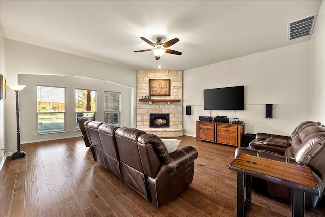 living room with hardwood / wood-style floors, ceiling fan, and a stone fireplace