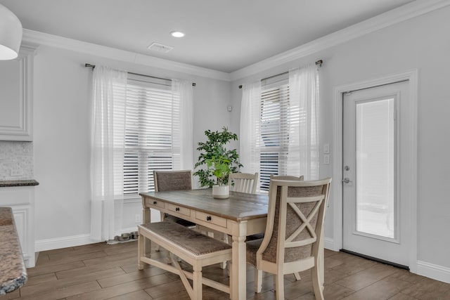 dining area with crown molding and light hardwood / wood-style floors