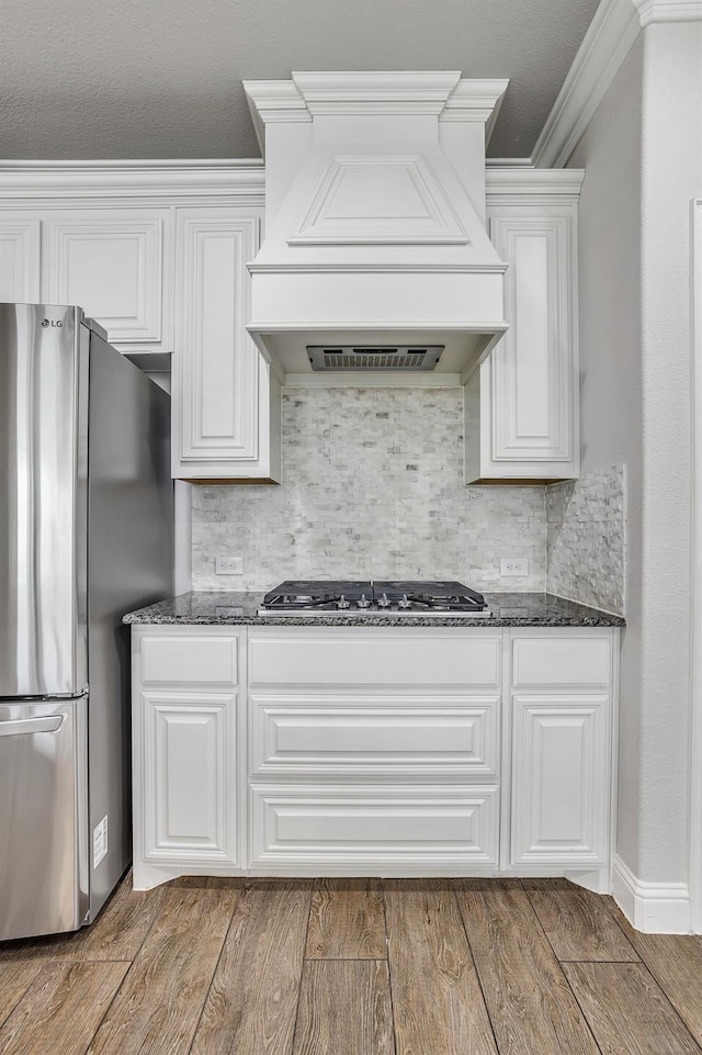 kitchen with premium range hood, hardwood / wood-style flooring, white cabinetry, and appliances with stainless steel finishes