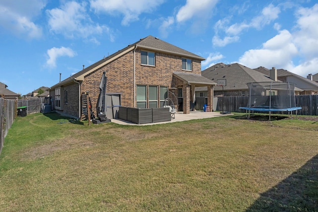 rear view of property featuring a lawn, an outdoor living space, a patio, and a trampoline