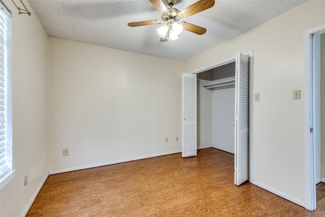 unfurnished bedroom with ceiling fan, a closet, a textured ceiling, and light hardwood / wood-style flooring