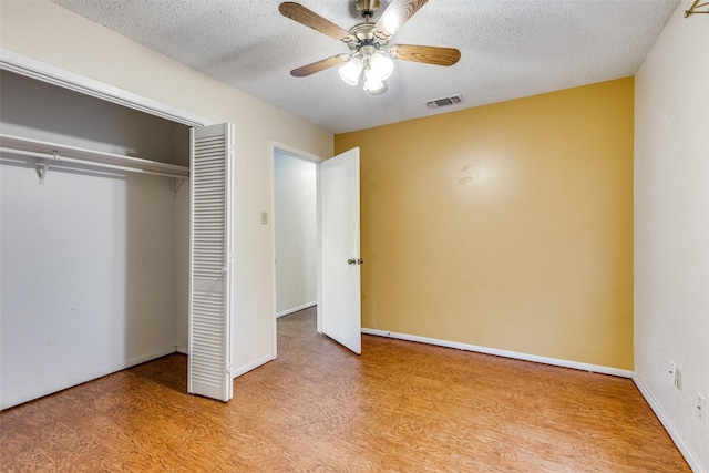 unfurnished bedroom with ceiling fan, light hardwood / wood-style flooring, a textured ceiling, and a closet