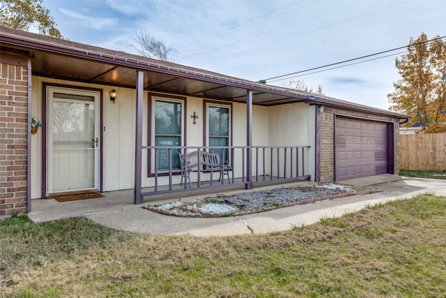 view of exterior entry with a porch, a garage, and a yard