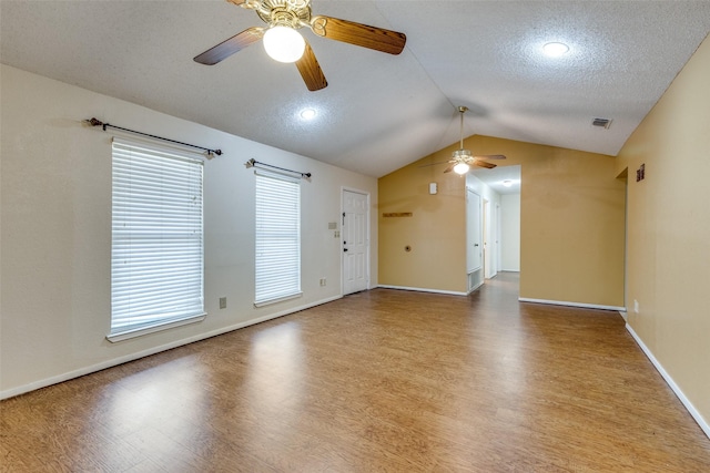 unfurnished room featuring hardwood / wood-style flooring, ceiling fan, lofted ceiling, and a textured ceiling