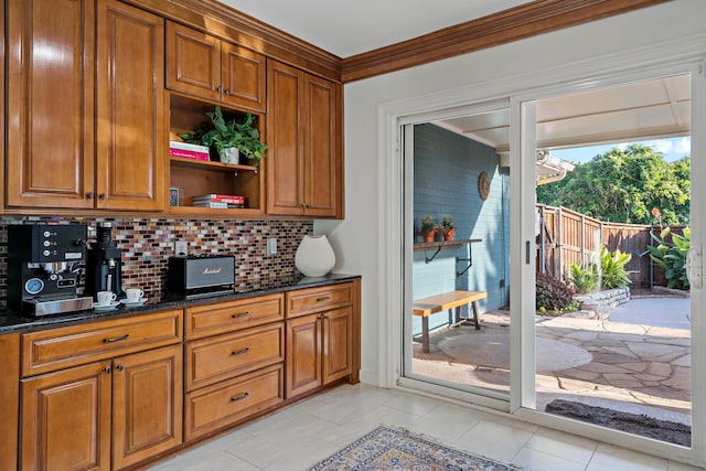 kitchen with ornamental molding, decorative backsplash, light tile patterned floors, and dark stone counters