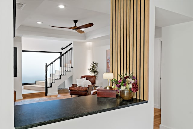 interior space with crown molding, ceiling fan, wood-type flooring, and a raised ceiling