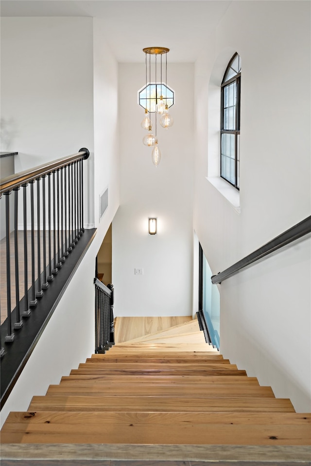 staircase with a chandelier and hardwood / wood-style floors