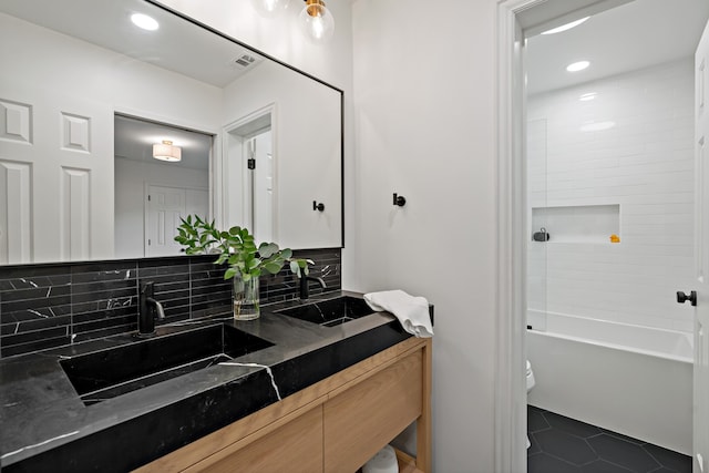 full bathroom featuring tasteful backsplash, toilet, tiled shower / bath, vanity, and tile patterned flooring