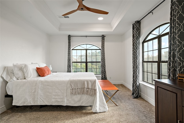 carpeted bedroom with multiple windows, crown molding, a raised ceiling, and ceiling fan