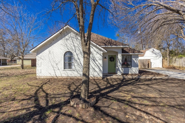 view of front of home with driveway, an outdoor structure, and brick siding