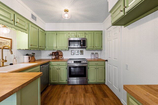 kitchen with kitchen peninsula, tasteful backsplash, stainless steel appliances, sink, and butcher block countertops