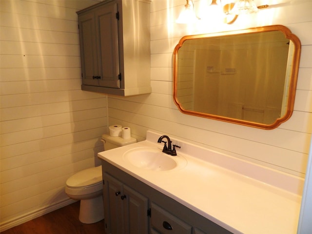 bathroom with wooden walls, vanity, wood-type flooring, and toilet