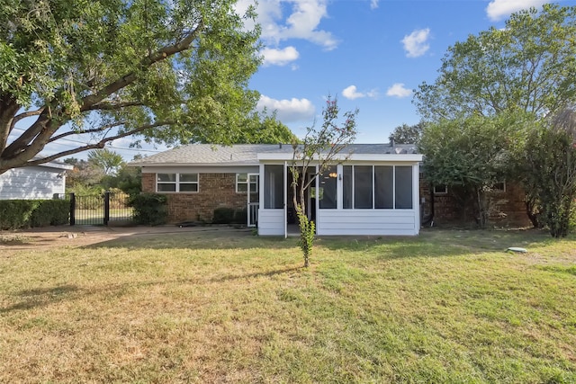 rear view of house featuring a sunroom and a lawn