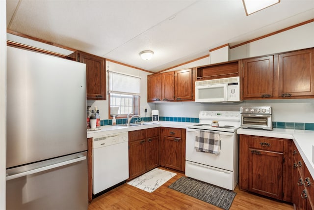 kitchen with white appliances, sink, vaulted ceiling, crown molding, and light hardwood / wood-style flooring