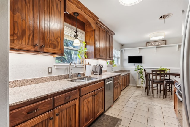 kitchen featuring stainless steel appliances, sink, light tile patterned flooring, pendant lighting, and light stone counters